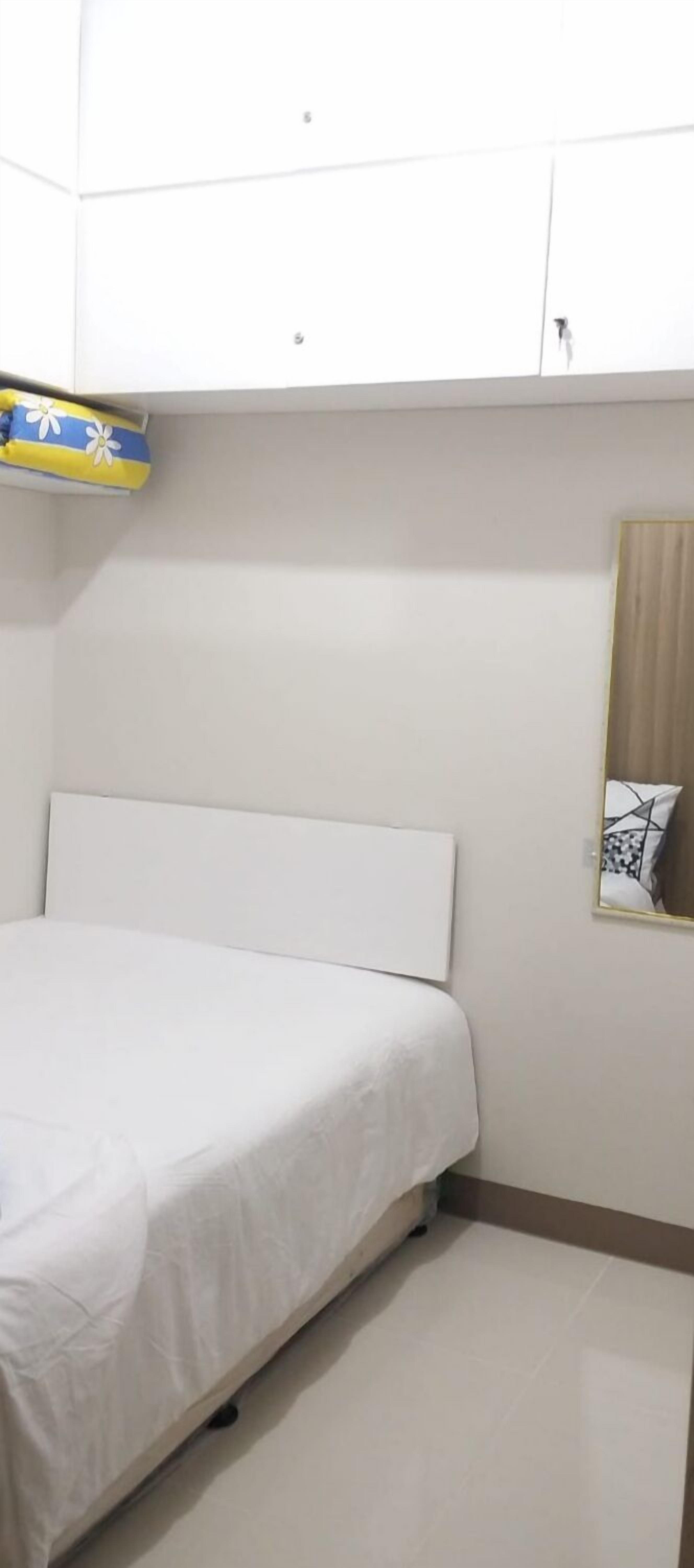 A bedroom with a bed, a wardrobe, and a mirror on the wall.