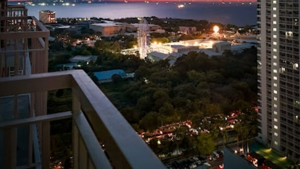 Un edificio alto con vistas a un paisaje urbano al atardecer, con el sol poniéndose sobre el agua.