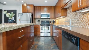 A modern kitchen with wooden cabinets, stainless steel appliances, and a granite countertop. - Heavenly Mountain Condo - Outdoor Hot Tubs & Steam Room (Canmore)
