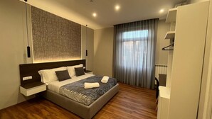 Un dormitorio moderno con una cama grande, una mesita de noche, un armario y una ventana con cortinas.