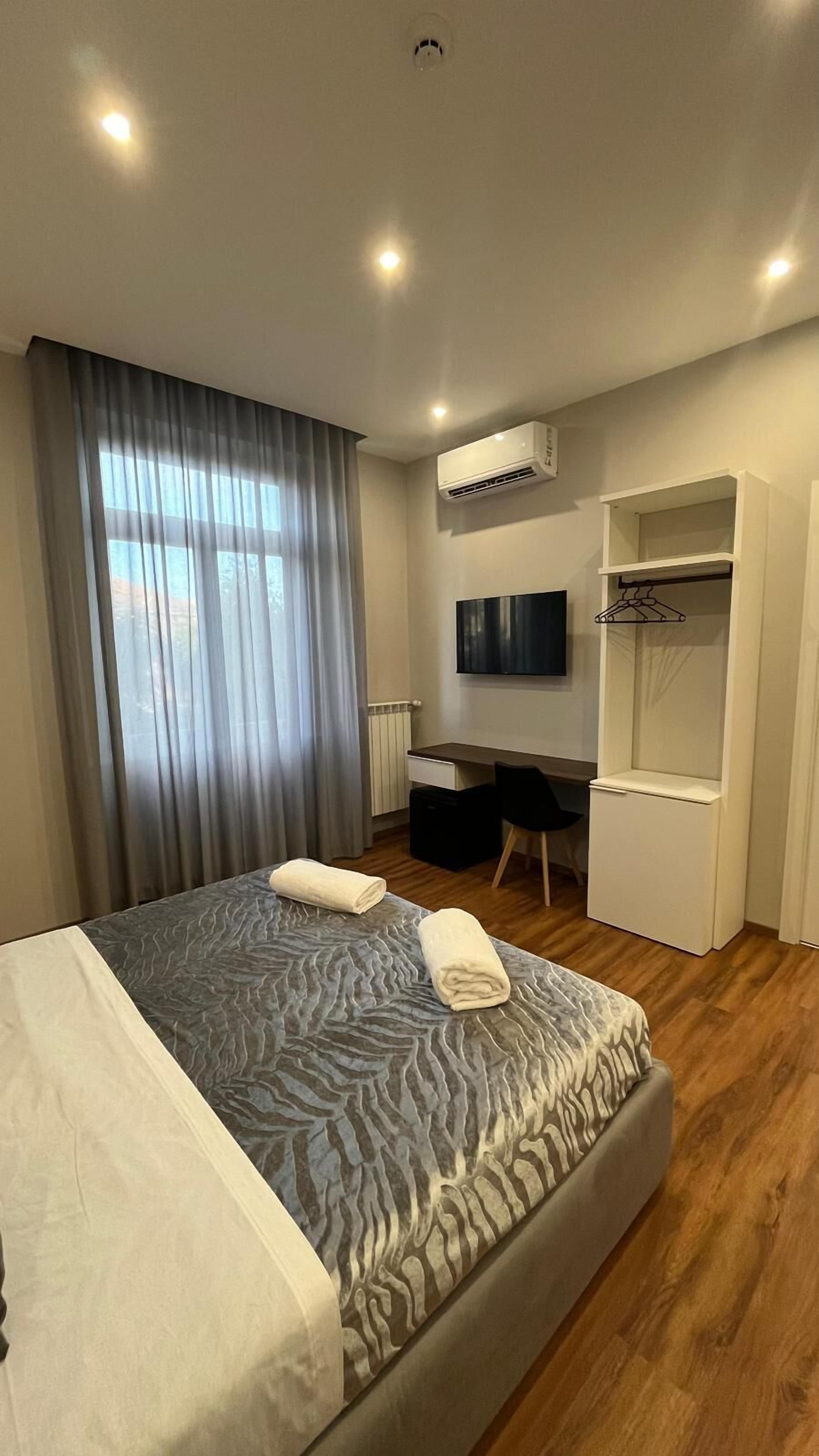 A hotel room with a bed, a desk, a television, and a wardrobe.