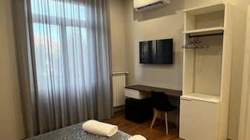 A hotel room with a bed, a desk, a television, and a wardrobe.