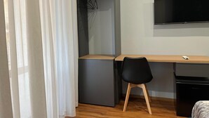 Una habitación pequeña con escritorio, silla y televisor montado en la pared.