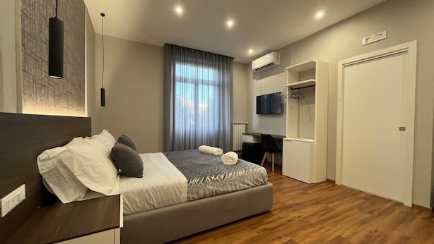 Una habitación de hotel moderna con cama, escritorio, televisión y armario.