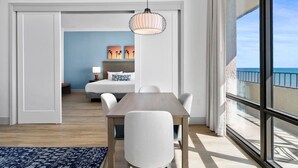 A modern hotel room with a dining area, a large window with a view of the sea, and a hanging light fixture. - Newly Renovated Coastal Living on the 17th Floor (Myrtle Beach)