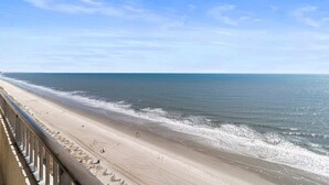 A beach with a railing, clear sky, and calm sea. - Newly Renovated Coastal Living on the 17th Floor (Myrtle Beach)