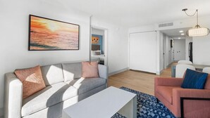 A modern living room with a gray sofa, a white coffee table, and a patterned rug.