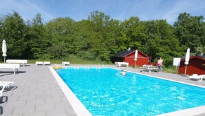 A swimming pool with a red building in the background, surrounded by trees. - "Cvetanka" - 200m from the sea by Interhome (Nexø)