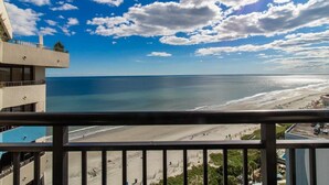 Ein Strandhotel mit Balkon mit Blick auf das Meer und den Strand.