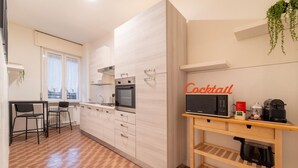 A modern kitchen with a microwave, oven, and a wooden coffee station. - Appartamento Gelso by Wonderful Italy (Como)
