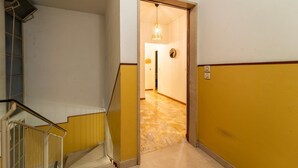 A hallway with a yellow wall, a white wall, and a marble floor. There is a door leading to another room. - Appartamento Gelso by Wonderful Italy (Como)
