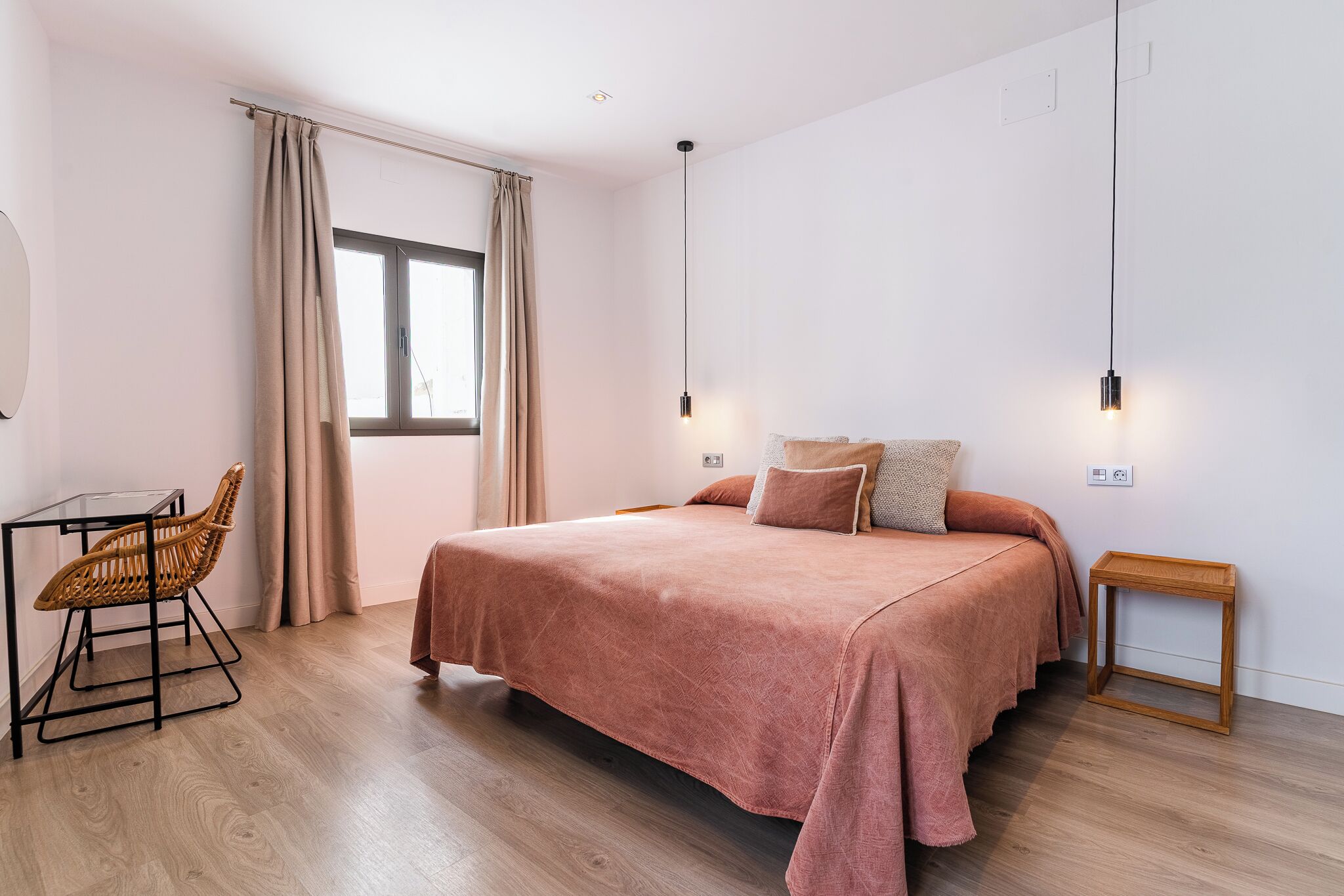 Une chambre à coucher avec un lit, une chaise, une table de chevet et une fenêtre avec des rideaux.