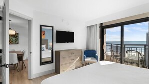 A hotel room with a large bed, a TV, a dresser, a desk with chairs, and a balcony with a view of the sea. - Seaside Delight 3 Flr 3BR Angle Ocean View Condo (Myrtle Beach)