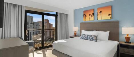 A hotel room with a large bed, two nightstands, a desk, and a balcony with a view of the city.