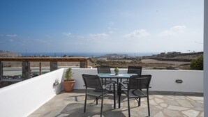 Una terraza con una mesa, sillas, una planta en maceta y vistas al paisaje.