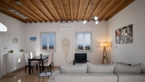 Una sala de estar con techo de madera, un sofá, una mesa de comedor con sillas, un televisor y una lámpara.