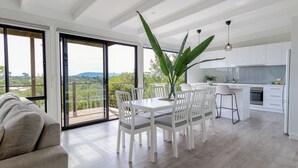 Een moderne keuken met witte kasten en een eethoek met een witte tafel en stoelen.