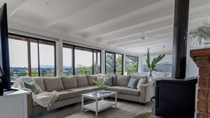 Een ruime woonkamer met een grote beige modulaire bank, een glazen salontafel en een open haard.