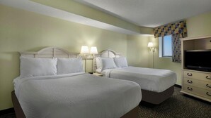 A hotel room with two beds, a television, and a window with curtains.