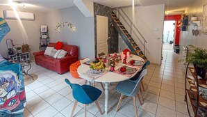 Ein Essbereich mit einem runden Tisch, blauen Stühlen und einer roten Couch im Hintergrund.