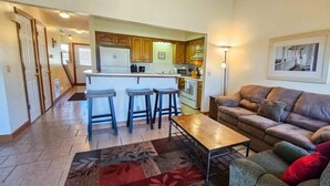 A living room with a sofa, a coffee table, and a kitchen in the background. - Great location for exploring Northwest Arkansas! (Holiday Island)