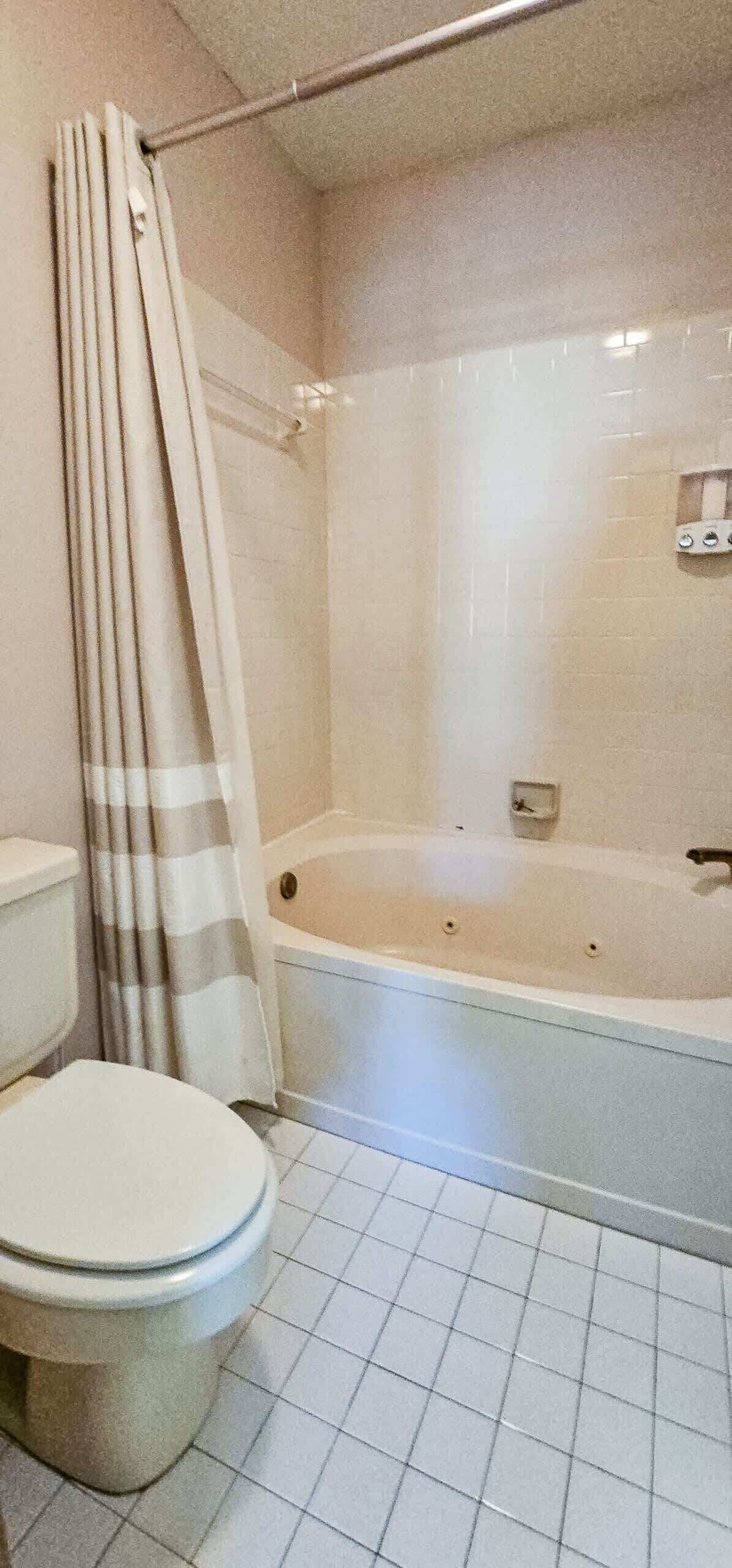 Un baño con inodoro, bañera y cortina de ducha.