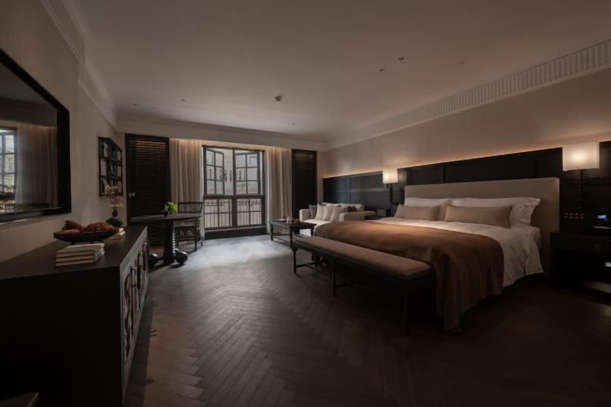 Une chambre d’hôtel moderne, dotée d’un grand lit, d’un bureau et offrant une vue sur l’extérieur.