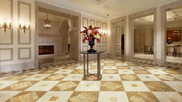 Eine großzügige Lobby mit einem Schachbrettmuster-Boden, einer zentralen Vase mit Blumen und einem Kamin.
