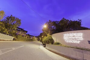 Een goed verlichte hotelinrit met een duidelijk bord waarop 