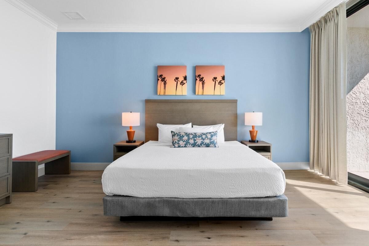 A large bed with a wooden headboard, two bedside tables with lamps, and a bench.