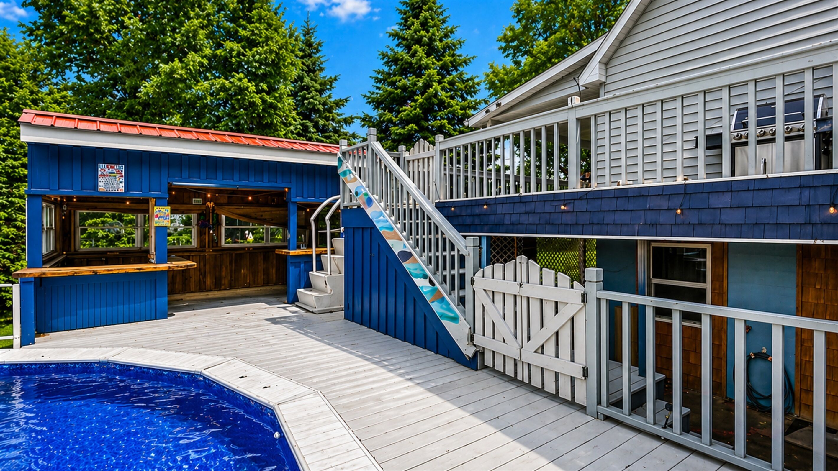 Un espace aménagé au bord de la piscine, comprenant un jacuzzi, une terrasse et un bâtiment à l’extérieur bleu et doté d’une terrasse en bois.