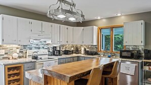 Une cuisine moderne avec des meubles blancs, un îlot central en bois et une grande fenêtre.