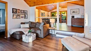 A cozy living room with a wooden ceiling, a sofa, a coffee table, and a side table. - Honeoye Cottage | 50' Lakefront | Dock | FLX (Honeoye)