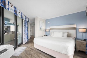 Habitación de hotel con una cama grande, lámparas de noche, una mesita de noche y vistas al exterior.