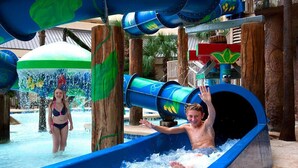 A water slide with a person sliding down and another standing nearby.