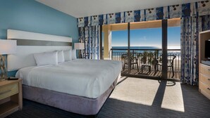 A hotel room with a large bed, a TV, a balcony with a view of the ocean, and a dining area. - Experience Serenity Oceanfront Suite 4th Floor (Myrtle Beach)
