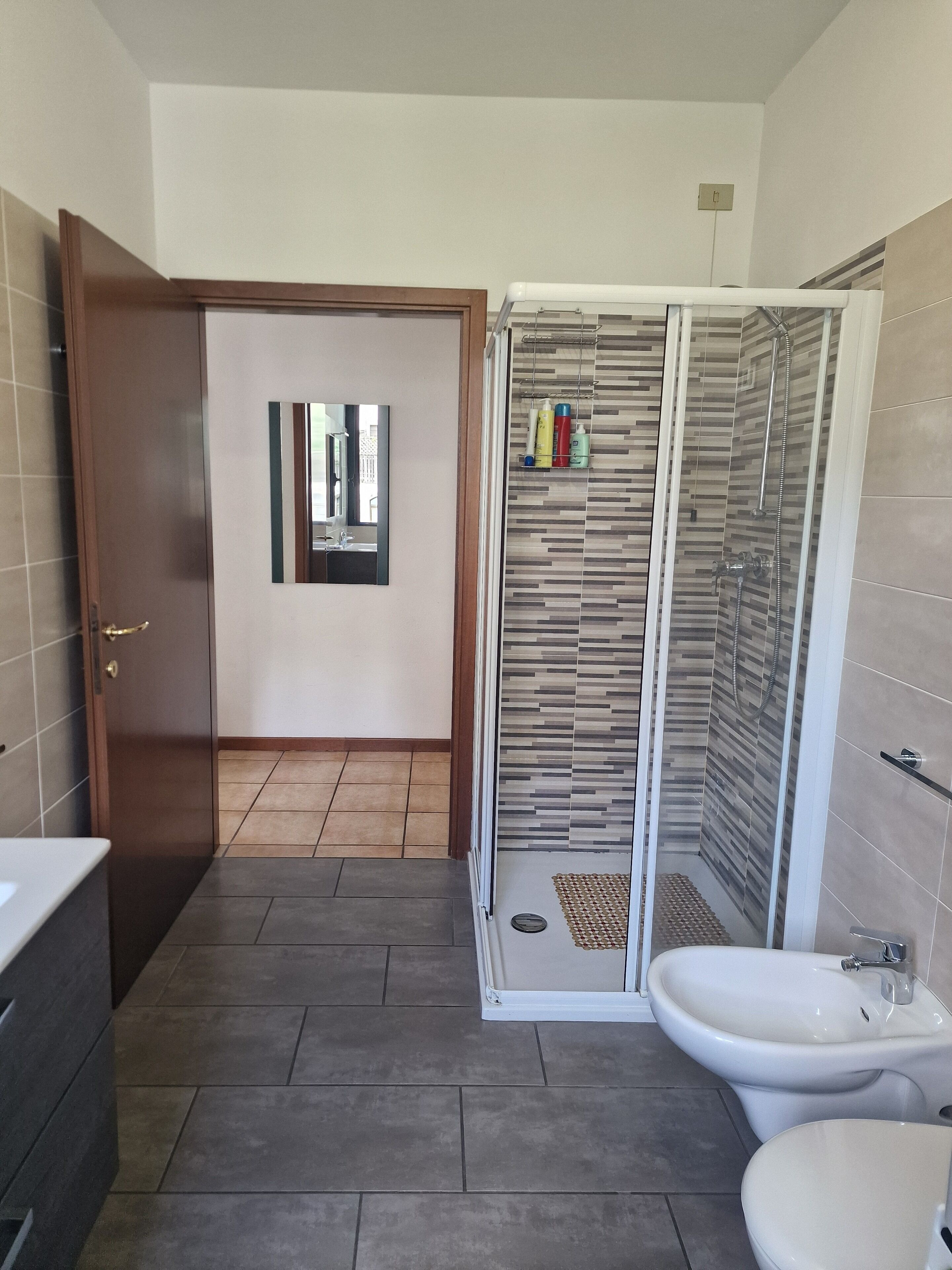 Een moderne badkamer met douche, toilet en wastafel.