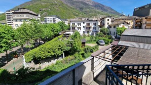 A residential area with a mountain in the background, featuring multi-story buildings with balconies and a mix of architectural styles. - Bernina Station Suite: 30 Steps to the Red Train (Tirano)