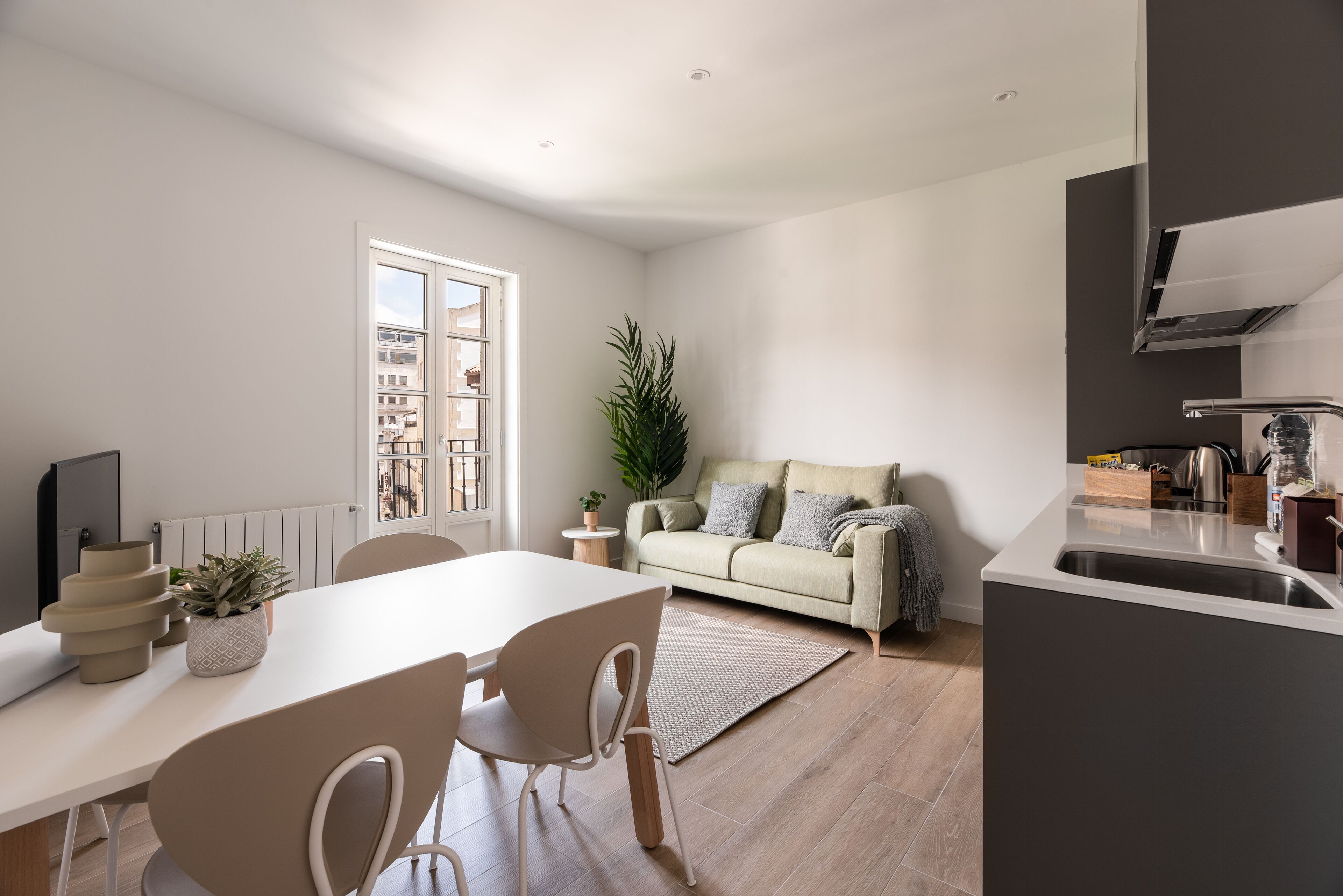 Una sala de estar moderna con una mesa de comedor, sillas, un sofá y una zona de cocina.
