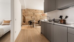 Una cuina moderna amb armaris grisos, una paret de pedra i zona de menjador amb taula i cadires.