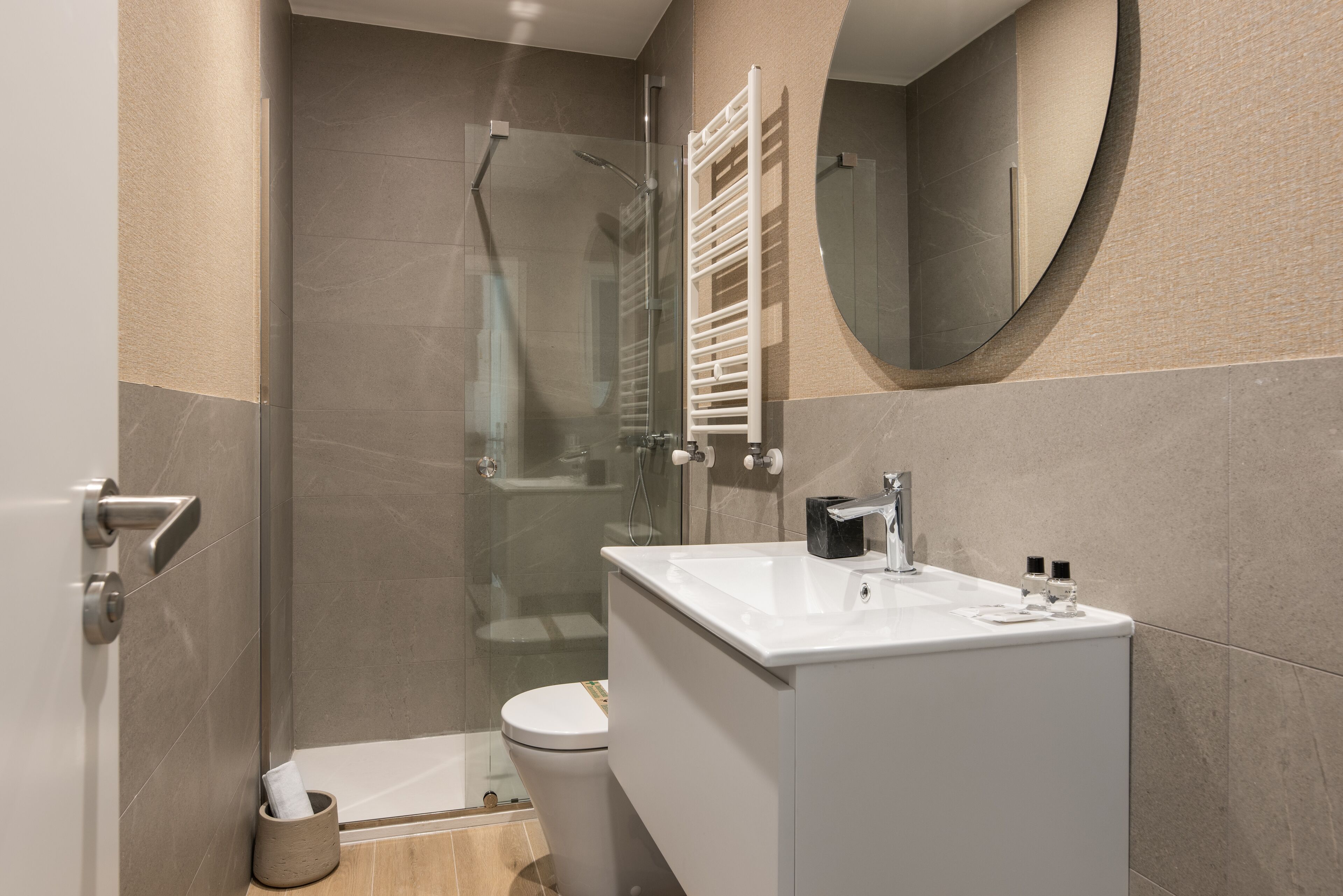 A modern bathroom with a glass shower enclosure, a white sink, and a toilet.