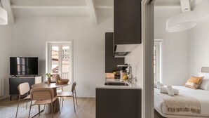 Un espai modern d'estar amb zona de menjador, cuina i sofà.