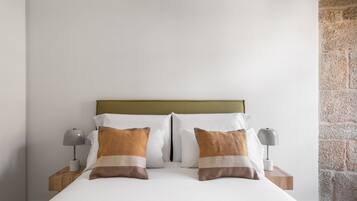 A neatly made bed with two pillows, a wooden headboard, and two bedside tables with lamps.