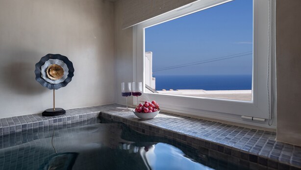 A swimming pool with a clear view of the ocean through a large window. - Centro Santorini (Santorini)