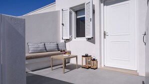 A modern outdoor seating area with a sofa and table, a door, and two lanterns. - Centro Santorini (Santorini)