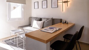 A modern living room with a wooden ceiling, a built-in bench, a dining table, and a wall-mounted light fixture. - Centro Santorini (Santorini)