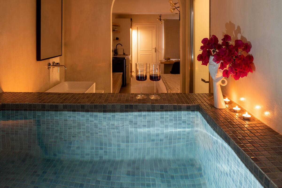 Un baño de hotel con piscina azulejada, lavamanos y espejo.