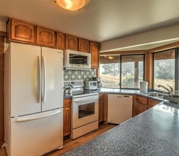 A kitchen with wooden cabinets, a stainless steel refrigerator, a microwave, a stove, and a dishwasher.