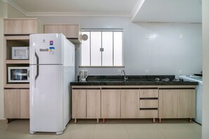 Eine moderne Küche mit integriertem Mikrowellenherd, Kühlschrank, Holzschr änken, einem Fenster und einer schwarzen Arbeitsplatte.