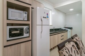 Una cocina equipada con microondas, horno, refrigerador, pileta y muebles de madera.